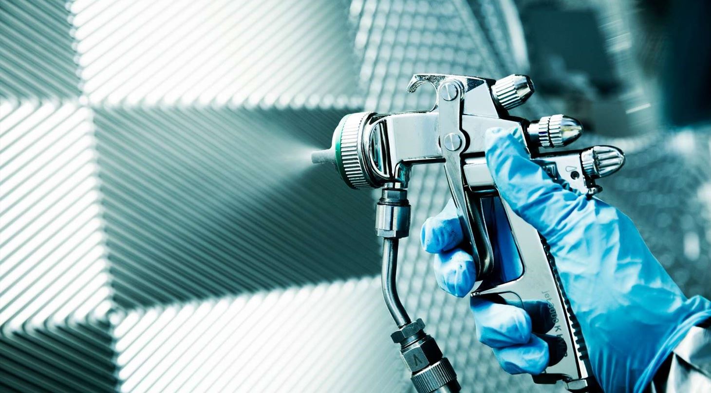 Hnd med spraydse foran metalplade